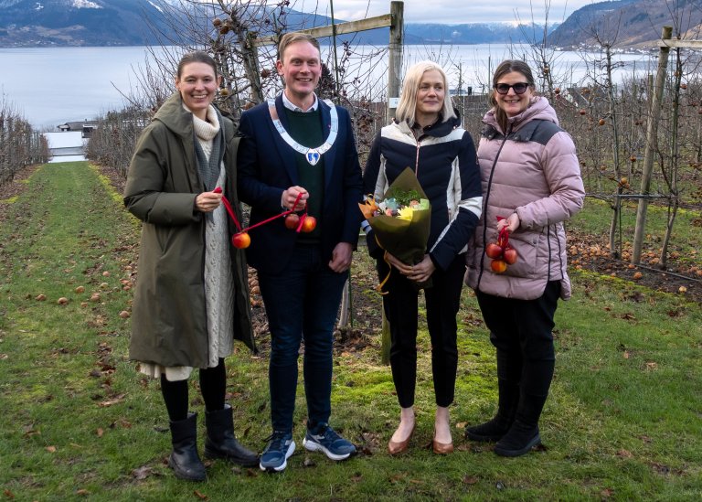 I januar 2026 var deltakarar frå mange ulike miljø innafor bevaringsarbeidet samla på Njøs frukt- og bærsenter på Leikanger ved lanseringa av den nye nasjonale klonbanken for frukt og bær. Ordførar i Sogndal, Stig Ove Ølmheim, klippa den epledekorerte snora. Frå venstre: Linn Borgen Nilsen, leiar for Norsk genressurssenter, NIBIO; Stig Ove Ølmheim, ordførar, Sogndal; Liv Hatleli Gilpin, leiar for Njøs frukt- og bærsenter og klonbank for frukt og bær og Svanhild Isabelle Batta Torheim, leiar for arbeidet med genressursar, LMD. Foto: Hege Ulfeng