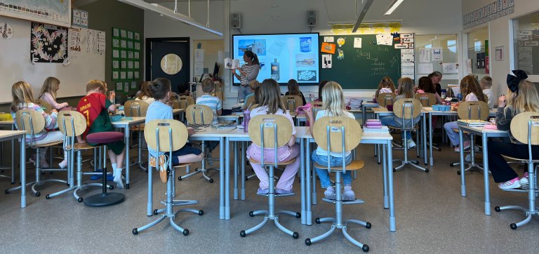Skoleklasse - elever ved pult.